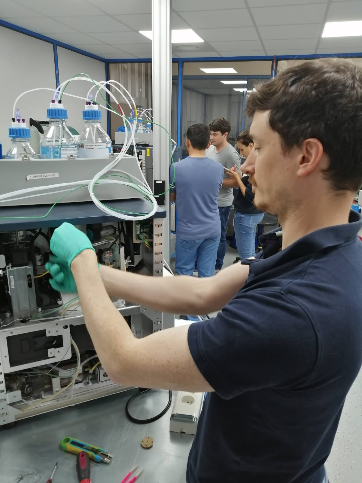 The VARLIS founder, gloved, working hands-on inside an analytical instrument in the laboratory